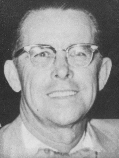 Smiling man wearing glasses and a suit.