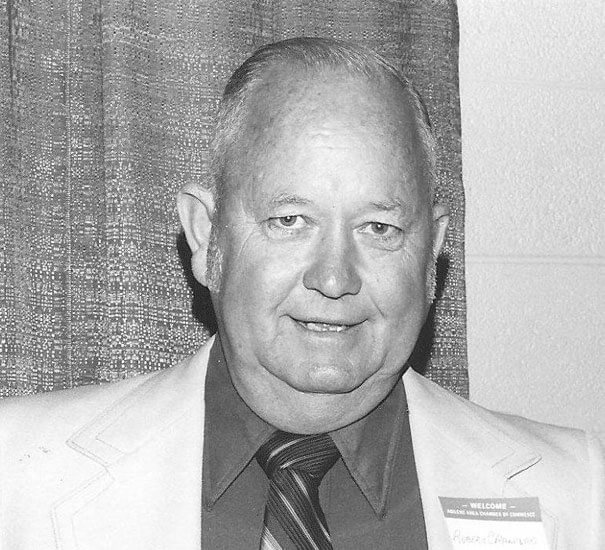Smiling man in suit with curtain background.