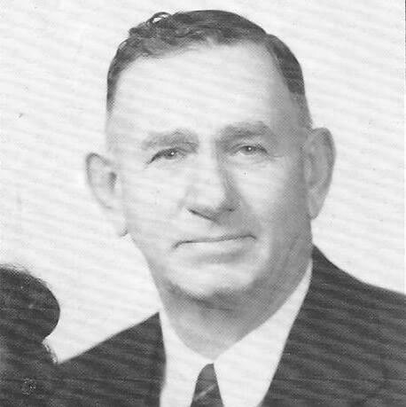 Smiling man in formal attire, vintage black-and-white portrait.