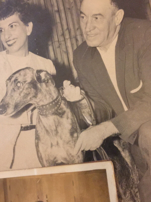 Man and woman with a greyhound, smiling warmly.