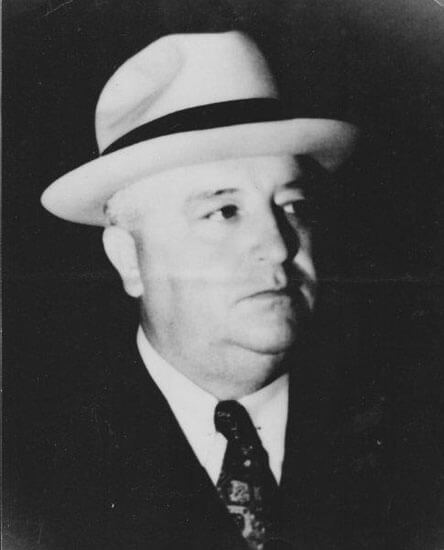 Man wearing a suit and hat, looking to side.