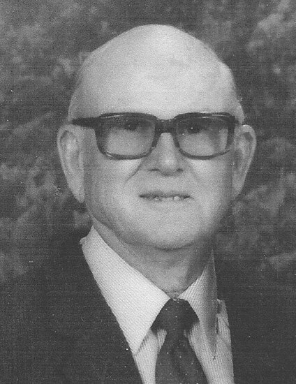 flyyn-alva Elderly man smiling, wearing glasses and a suit.