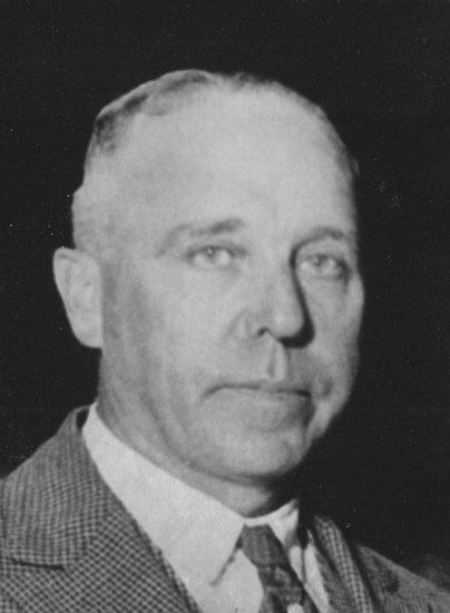 Man in suit gazing forward with neutral expression.