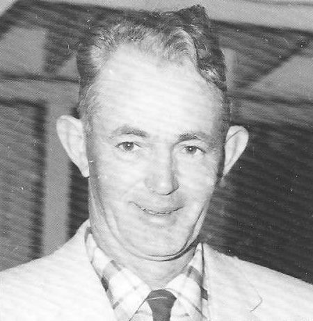 gavan-michael-joseph Man smiling, wearing suit and checkered shirt.