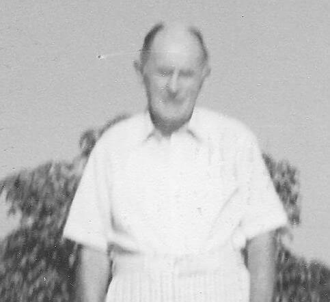Man standing outdoors, wearing a light shirt.