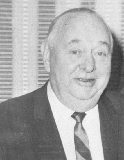 Smiling elderly man in a suit and tie.