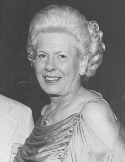 Smiling woman with elegant hairstyle and dress.