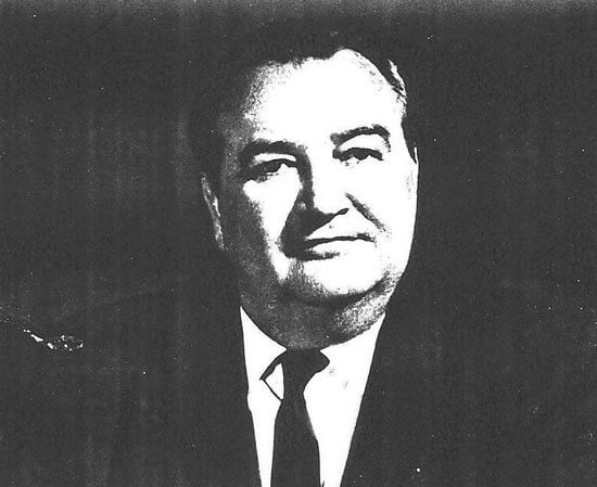 knight-james-c Man in suit, smiling, against a dark background.