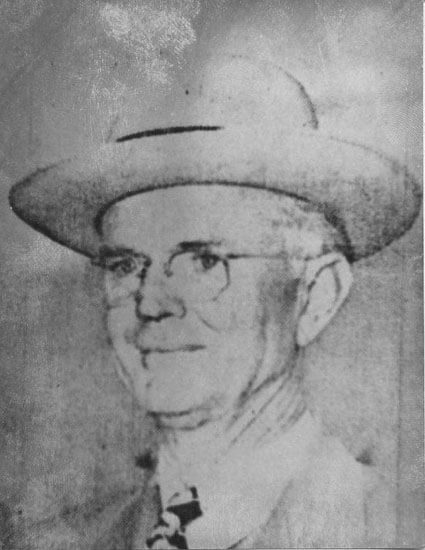 Elderly man wearing a hat, smiling slightly.