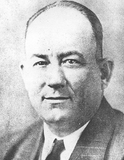 Man in suit, serious expression, black and white portrait.