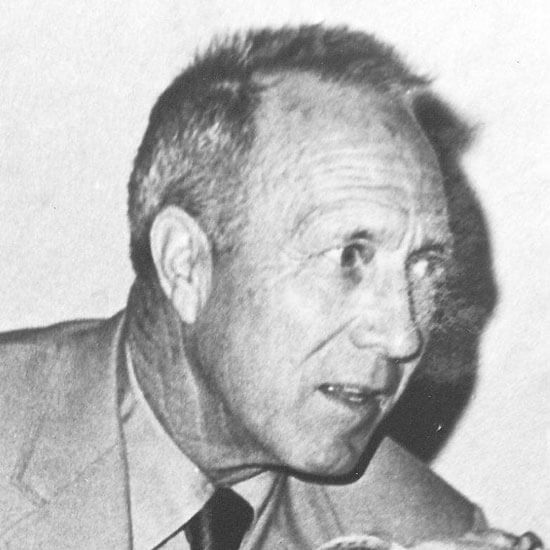 Man in suit speaking intently, black and white photo.