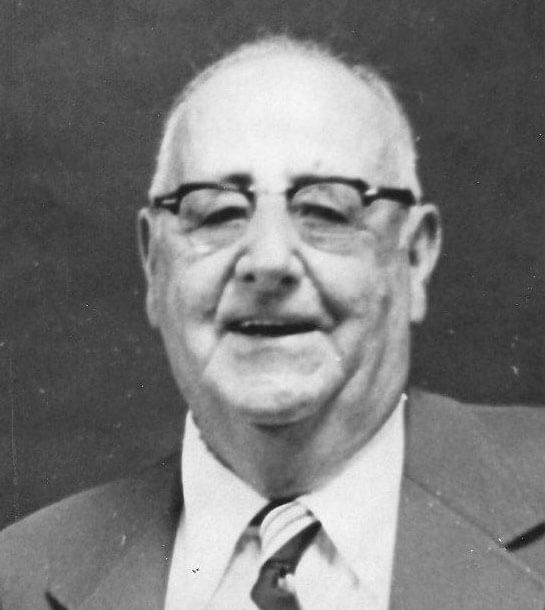 Smiling elderly man wearing a suit and glasses.