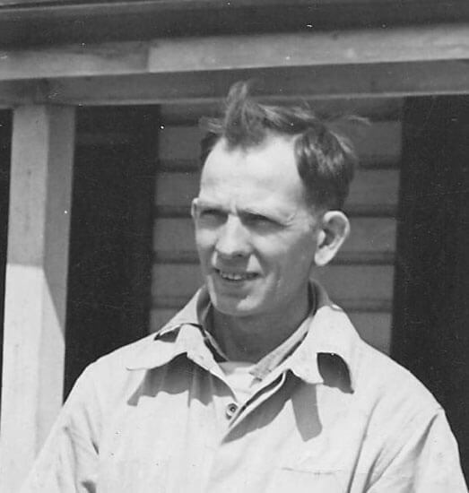 Man standing outdoors, wearing a collared shirt, smiling.
