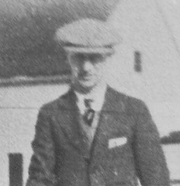 mollerup-richard Man in suit and hat standing outside building.