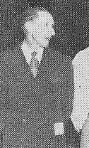 Man standing in suit, looking to the side.