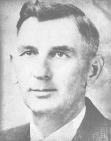 Man in formal attire looking forward, black and white.