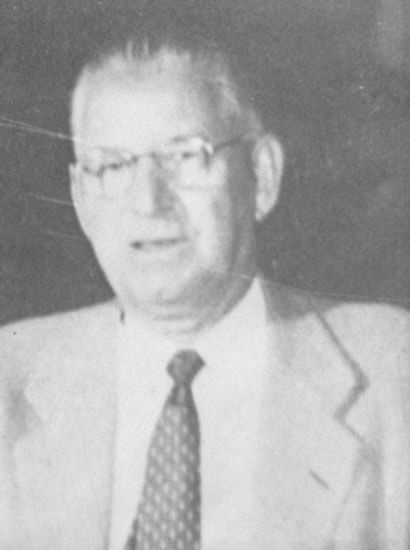 Man in suit smiling slightly in vintage photograph.