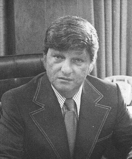 Man sitting at a desk, looking serious.