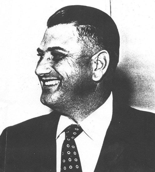 Smiling man in suit, looking to the side.