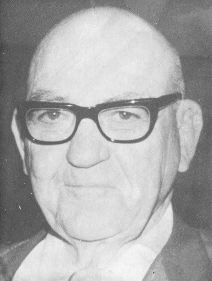 Elderly man with glasses, looking directly at camera.