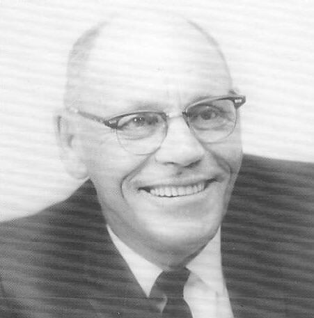 Smiling man wearing glasses and suit.