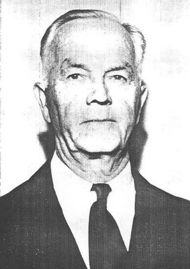 Elderly man in suit looking directly at camera.