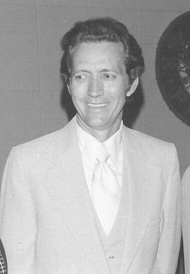 Smiling man in suit standing indoors.