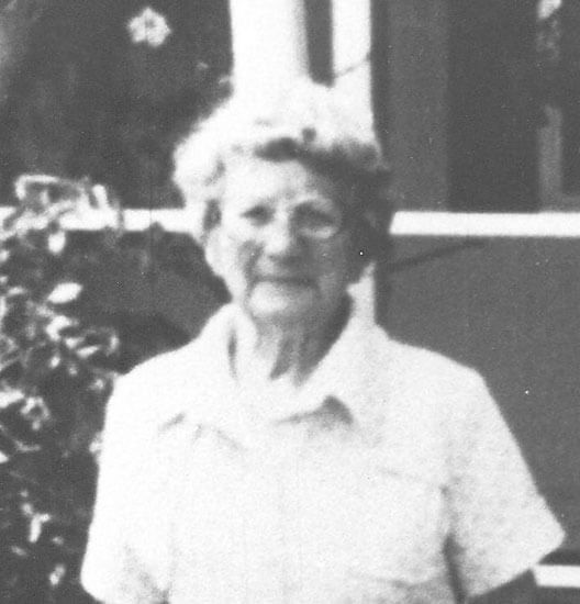 weiss-pansy Elderly woman smiling outside, wearing a collared shirt.