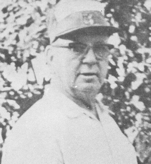 Elderly man wearing hat and glasses outdoors.