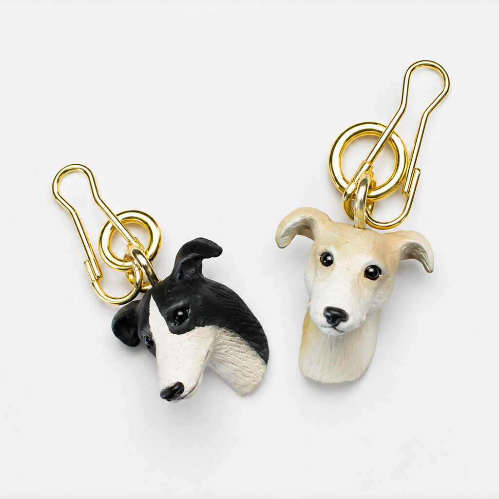 Two greyhound head keychains with gold clasps.